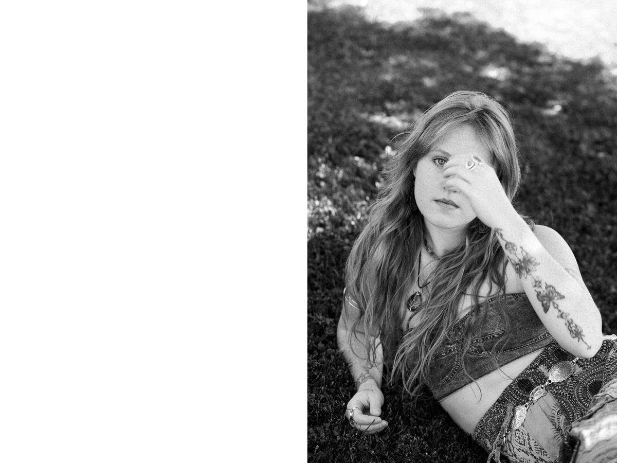 Spread 1 of 3 from Summer Siren: a woman in a boho crop top covers one eye with her hand, seated outdoors; black and white.