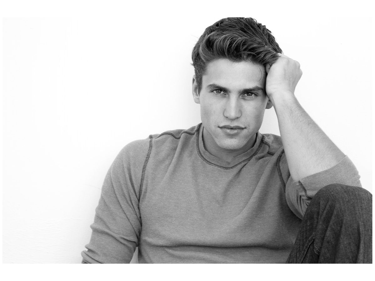 Spread 3 of 8 from Mayers Mark: a close portrait of a young man in a sweater, hand in his hair, looking at the camera; black and white.