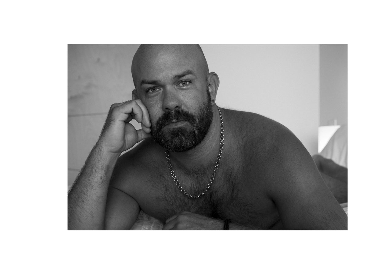 Spread 3 of 11 from Palm Springs, CA: a close portrait of a bearded, bald man resting his head on his hand, wearing a chain necklace; black and white.