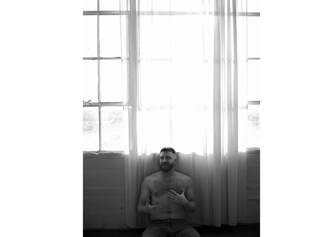 Spread 3 of 10 from Studio Sessions: a bearded, shirtless man sits cross-legged against a bright curtained window; black and white.