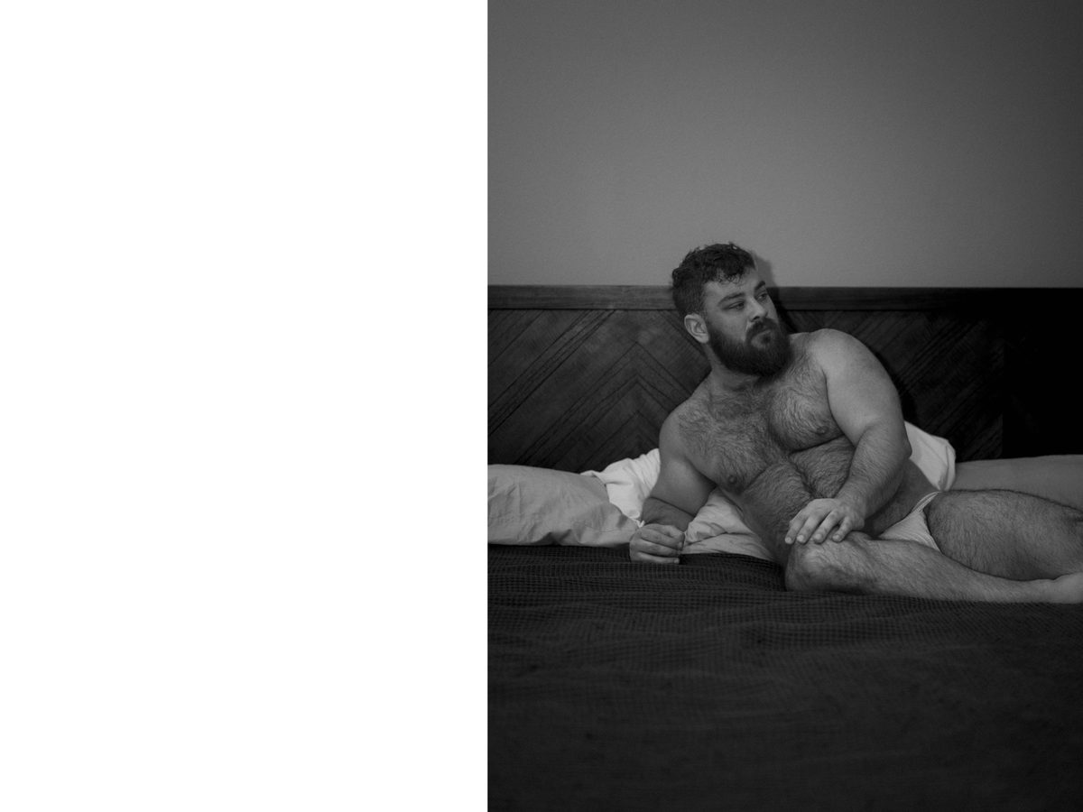 Spread 2 of 10 from Bear Bottom: a heavyset, bearded man reclines against pillows on a bed; black and white.